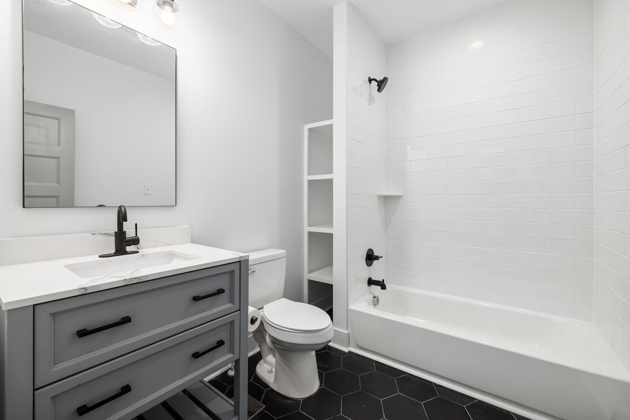 creative-01 Sleek modern bathroom featuring a white bathtub, sink, toilet, and elegant fixtures.
