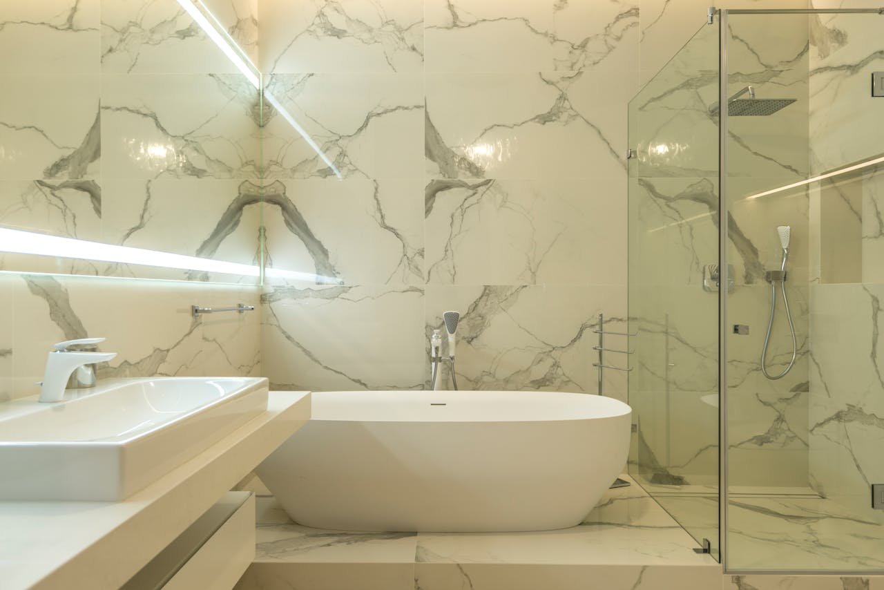 creative-02 Elegant marble bathroom featuring a bathtub, sink, and glass shower enclosure.