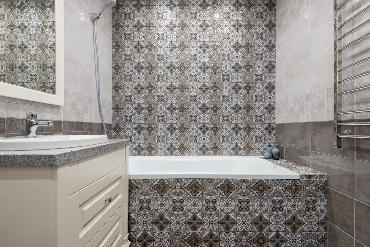 brand-03 Luxurious bathroom featuring ornate patterned tiles, a sleek bathtub, and modern fixtures.